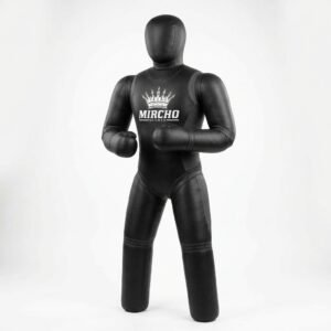 A black grappling dummy standing upright in a studio setting for MMA training.