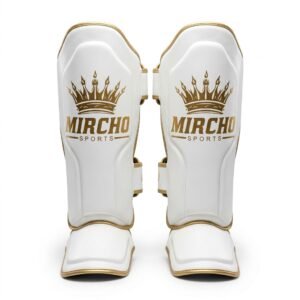 Pair of white and gold MMA shin guards with secure straps and integrated foot padding.